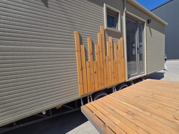 Casa móvil con paneles de madera en una pared y una mesa de madera en primer plano.