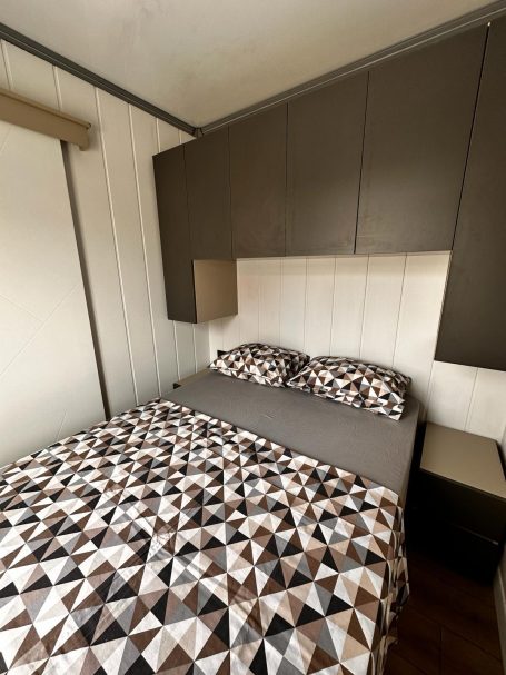 Dormitorio con cama doble y almacenamiento superior Dormitorio doble con armarios superiores y ropa de cama geométrica