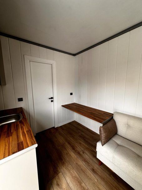 Espacio comedor con mesa integrada Cocina minimalista con pared blanca, mesa de madera y sofá en una esquina.