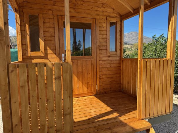 Acceso delantero con porche cubierto Cabin de madera vacía con porche y ventanas, rodeada de naturaleza.